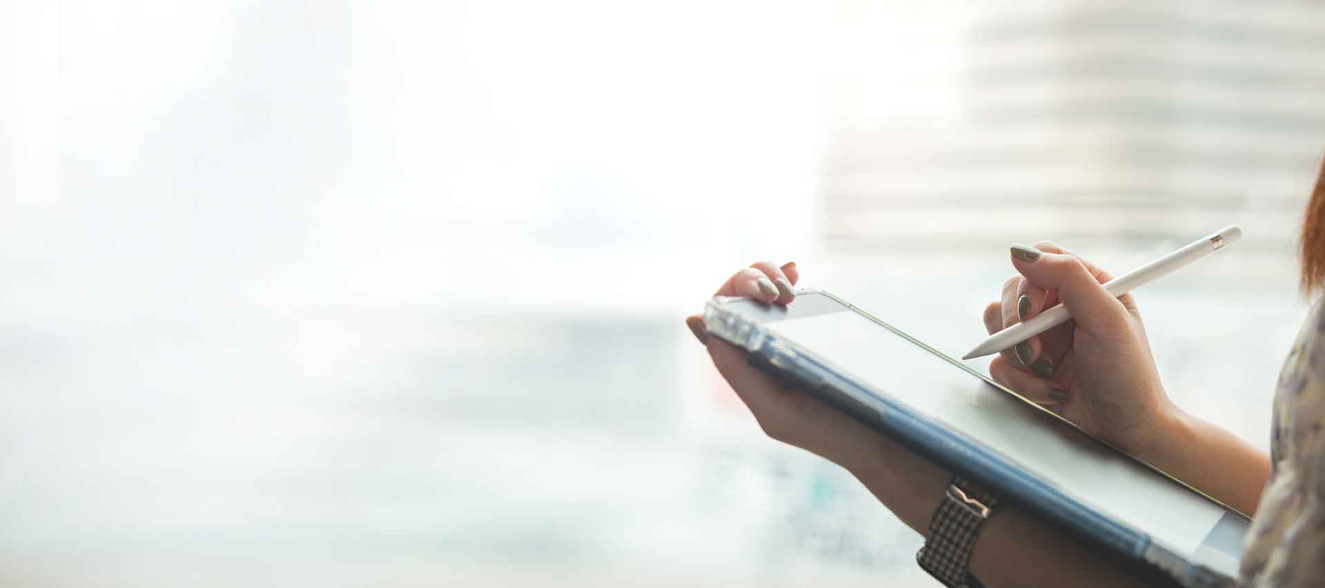 Frau hält Tablet und schreibt mit einem Touch-Pen