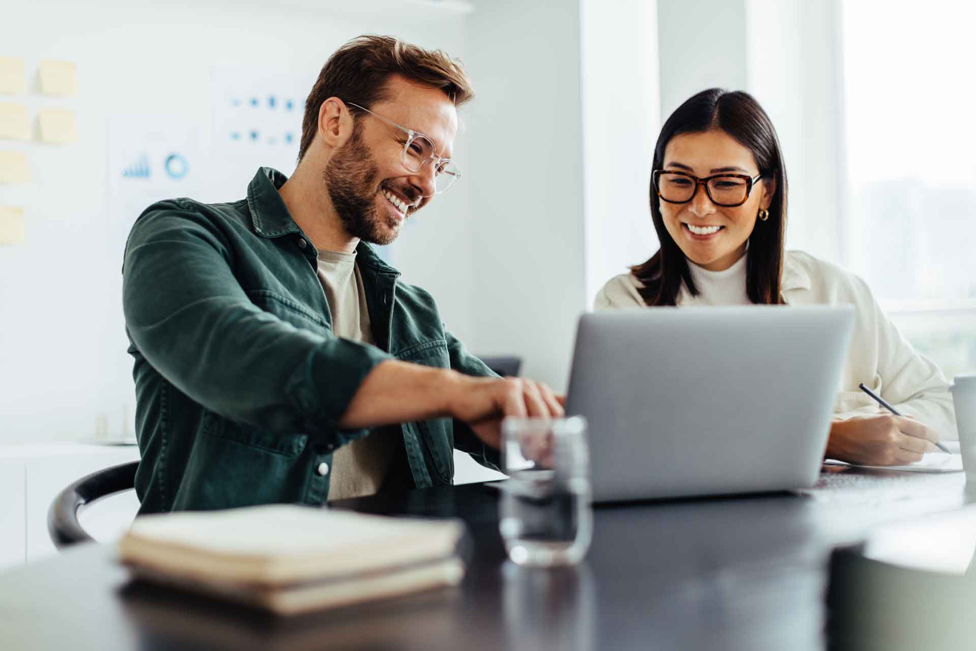 Digitales Vertragsmanagement - Frau und Mann arbeiten zusammen. Er zeigt etwas auf dem Laptop.